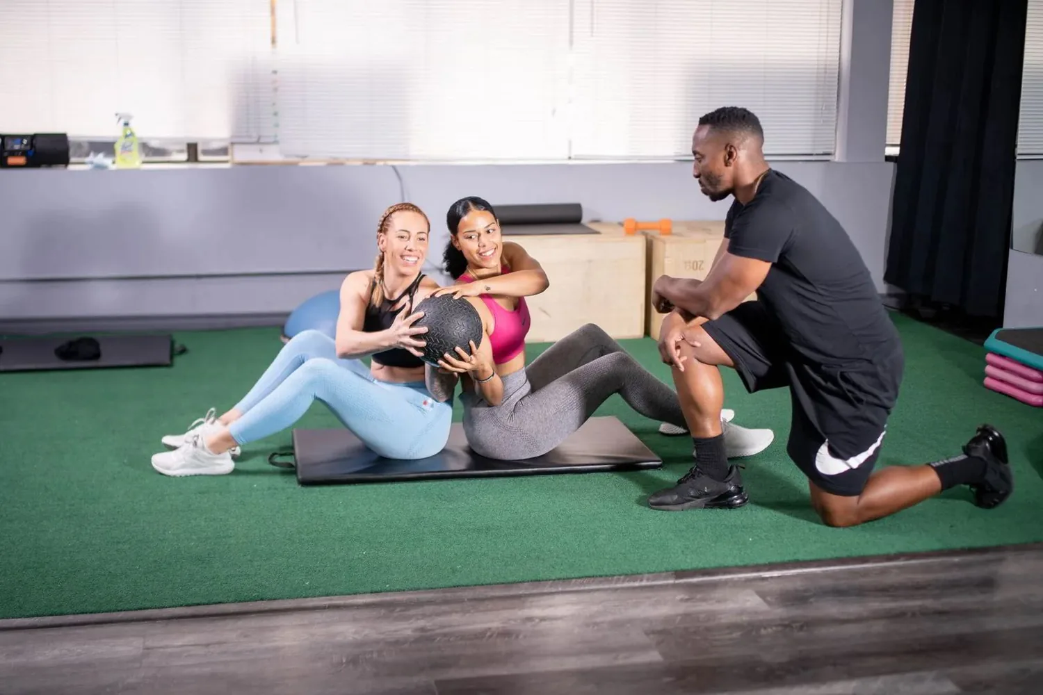 A QuikTrain coach guiding a small group of adults through dumbbell and kettlebell work on the training floor in Markham